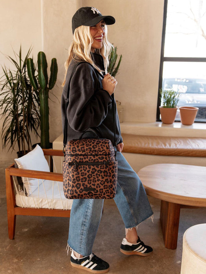 Person wearing a leopard print lunch bag on their shoulder in an indoor setting