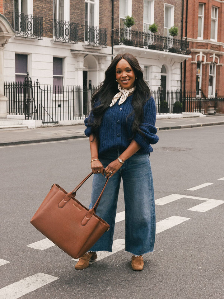 Poppy & Peonies Double Duty Tote in Chestnut carried by the top handles while standing on a city street.