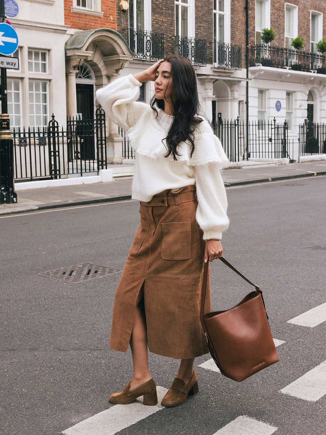 Woman walking with the Poppy & Peonies The Bucket Bag in Chestnut carried by the shoulder strap on a London street.