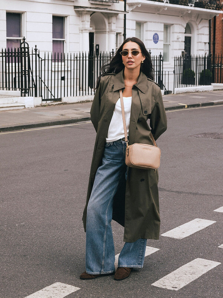 Woman standing with the Poppy & Peonies 24/7 Crossbody in Taupe worn across her body on a city street.