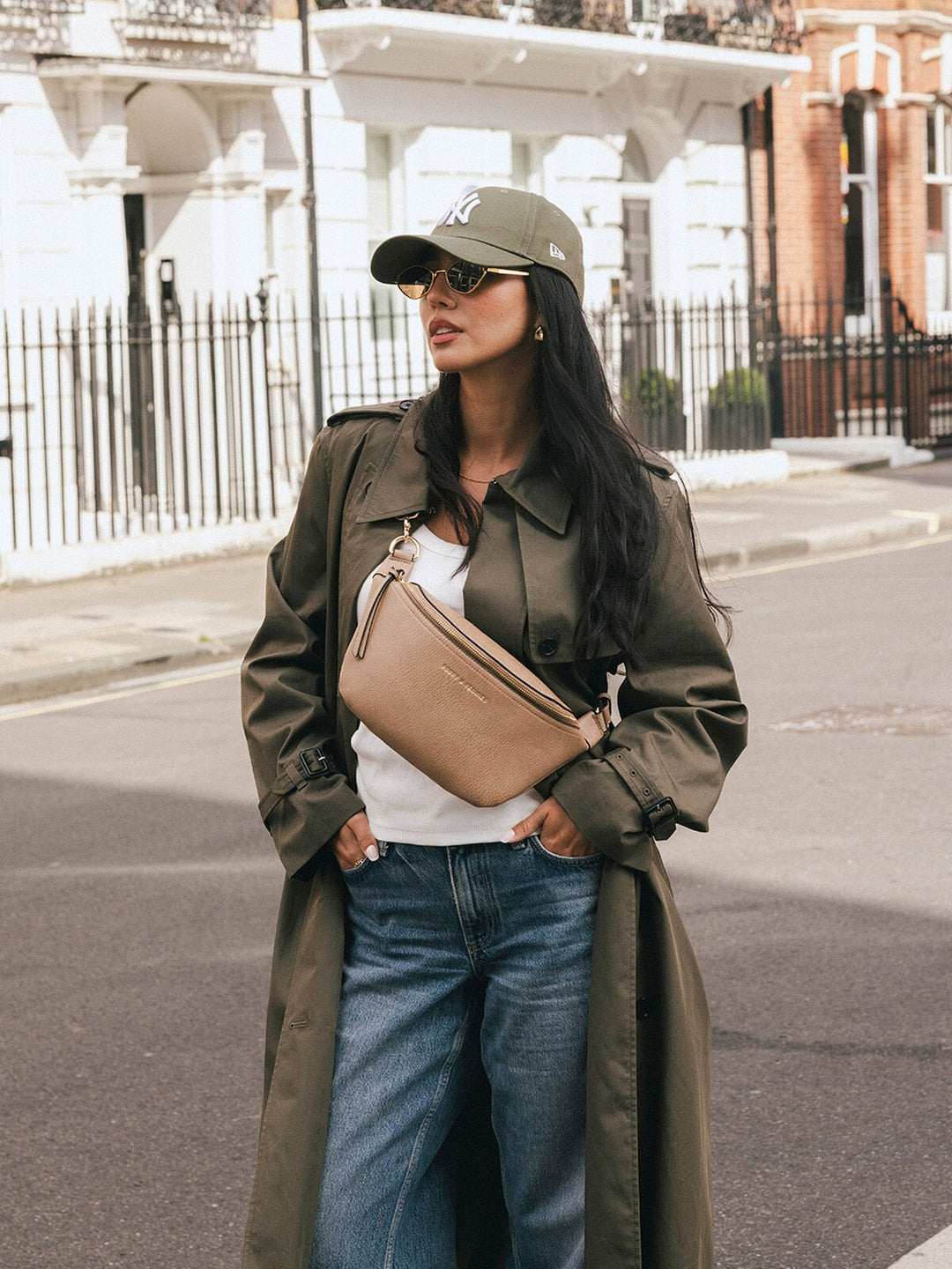 Woman wearing the Poppy & Peonies The Sidekick in Taupe across her chest while posing on a city street.