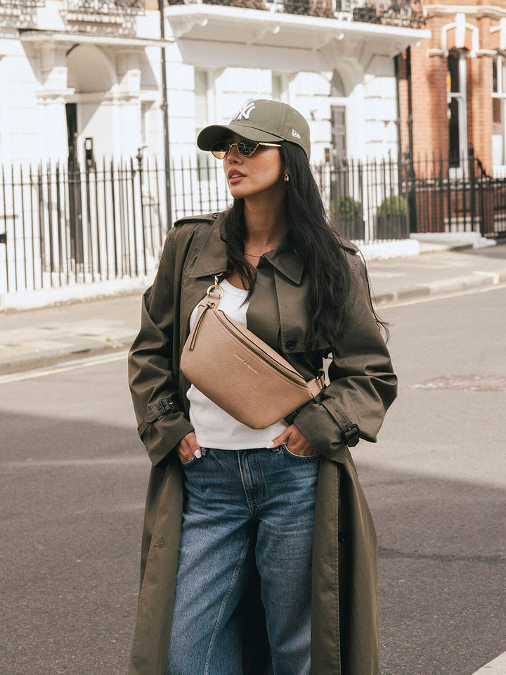 Woman wearing the Poppy & Peonies The Sidekick in Taupe across her chest while posing on a city street.