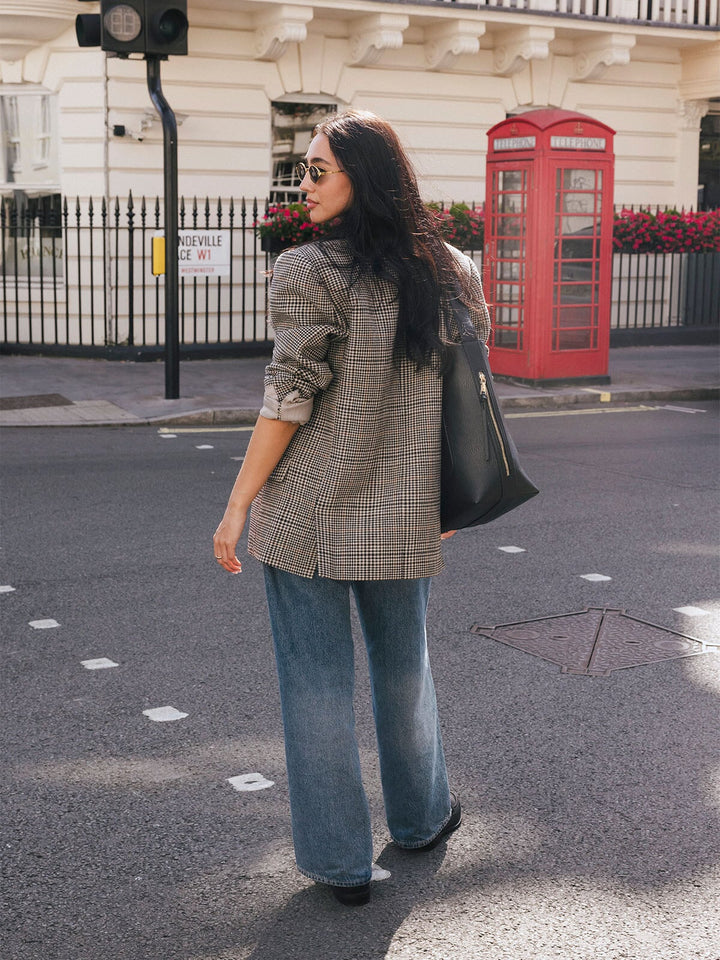 Woman walking with the Poppy & Peonies The Bucket Bag in Black carried over her shoulder on a city street.