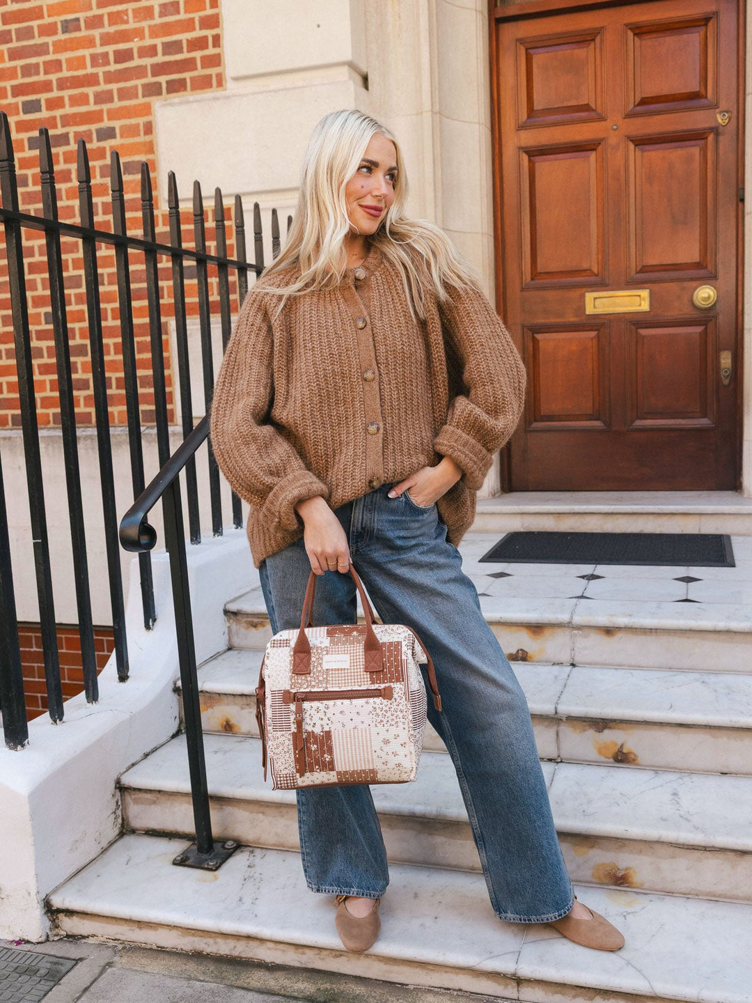 Full-body lifestyle shot of a woman carrying the Poppy & Peonies Lunch Bag in Brown Patchwork by the top handle while standing on outdoor steps.