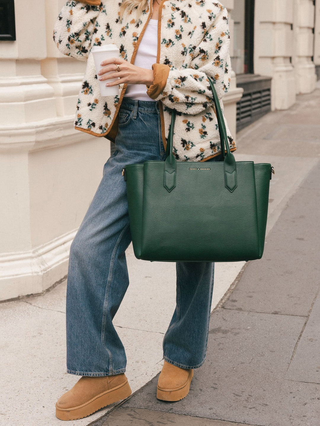 Woman carrying the Poppy & Peonies Double Duty Tote in Heritage Green by the top handles with a casual everyday outfit.