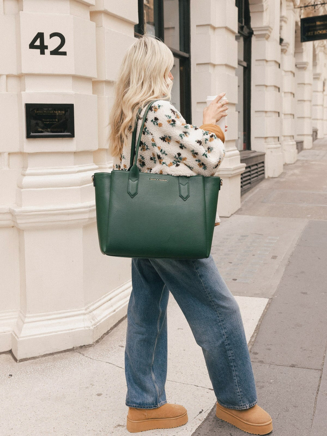 Side view of a woman carrying the Poppy & Peonies Double Duty Tote in Heritage Green over the shoulder with the top handles.