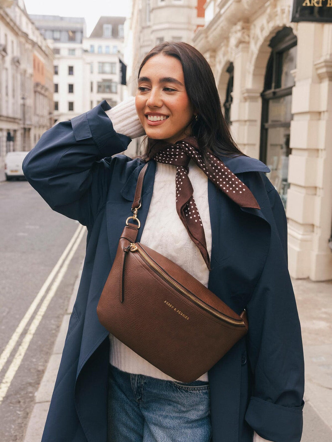 Lifestyle shot of a woman wearing the Poppy & Peonies Large Sidekick in Espresso crossbody, highlighting the oversized silhouette and front zipper.