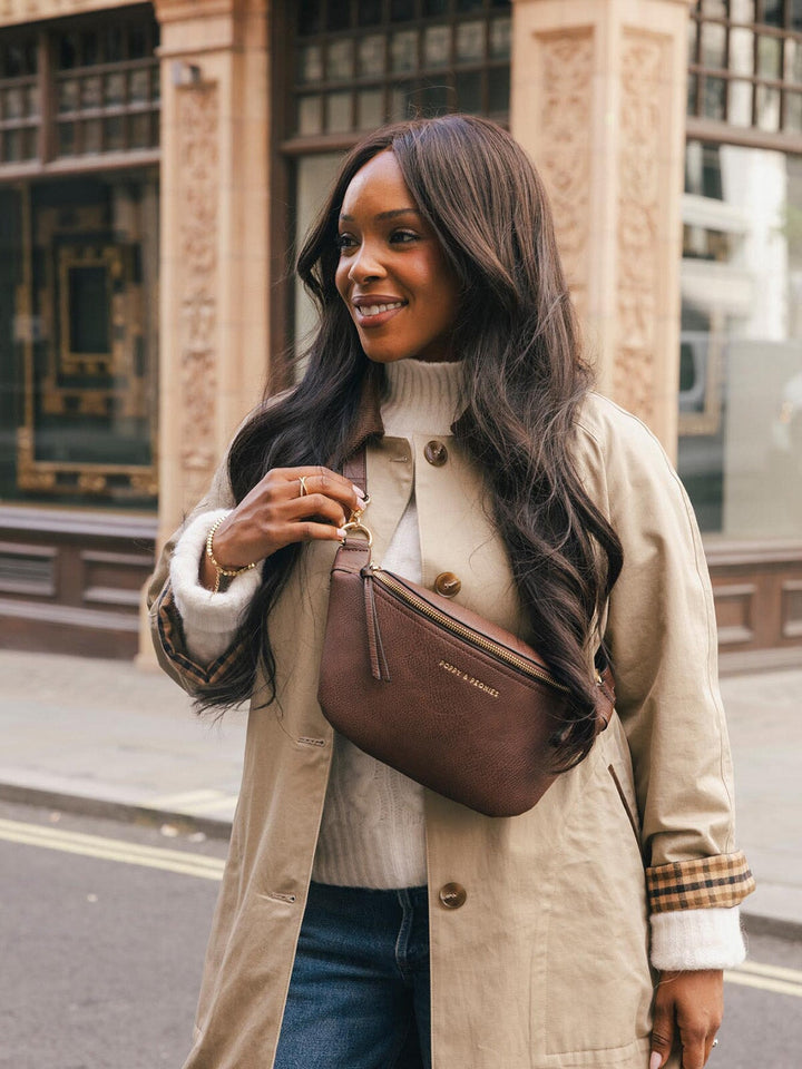 Close-up lifestyle shot of a woman wearing the Poppy & Peonies Sidekick in Espresso crossbody, highlighting the front zipper and compact silhouette.