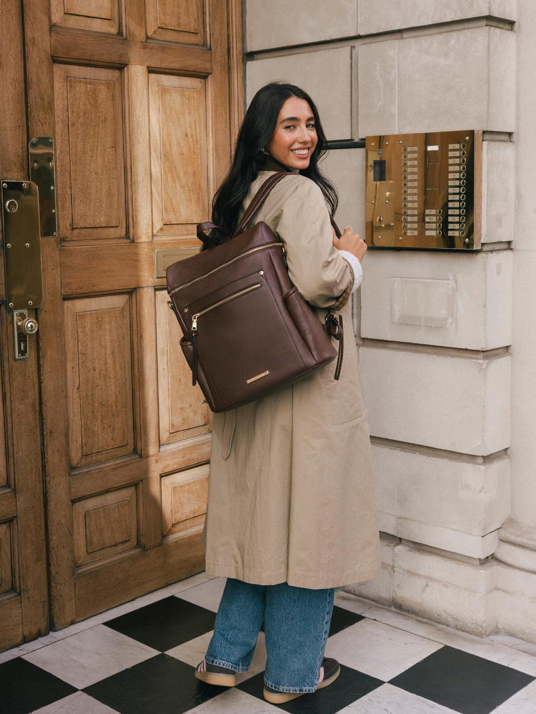 Woman looking back while wearing the Poppy & Peonies Commuter Backpack in Espresso over both shoulders.