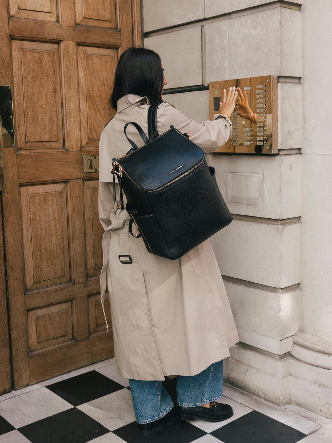Back view of a woman wearing the Poppy & Peonies Carryall Backpack in Black over both shoulders.