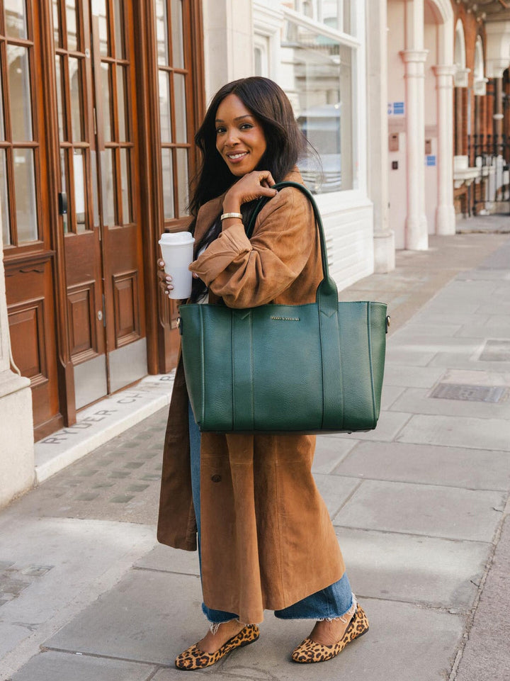 Woman carrying the Poppy & Peonies Multitasker in Heritage Green over her shoulder, showing the structured tote silhouette.