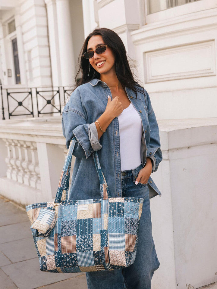 Woman carrying the Poppy & Peonies Daydreamer Tote in Navy Patchwork over her shoulder, showing the spacious tote silhouette and side pocket.