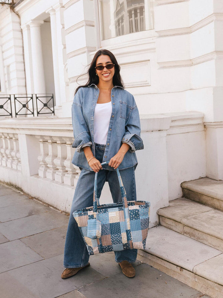 Woman posing with the Poppy & Peonies Daydreamer Tote in Navy Patchwork carried by the top handles.