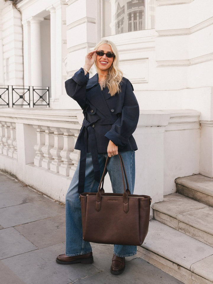 Woman standing with the Poppy & Peonies Double Duty Tote in Espresso held by the top handles.