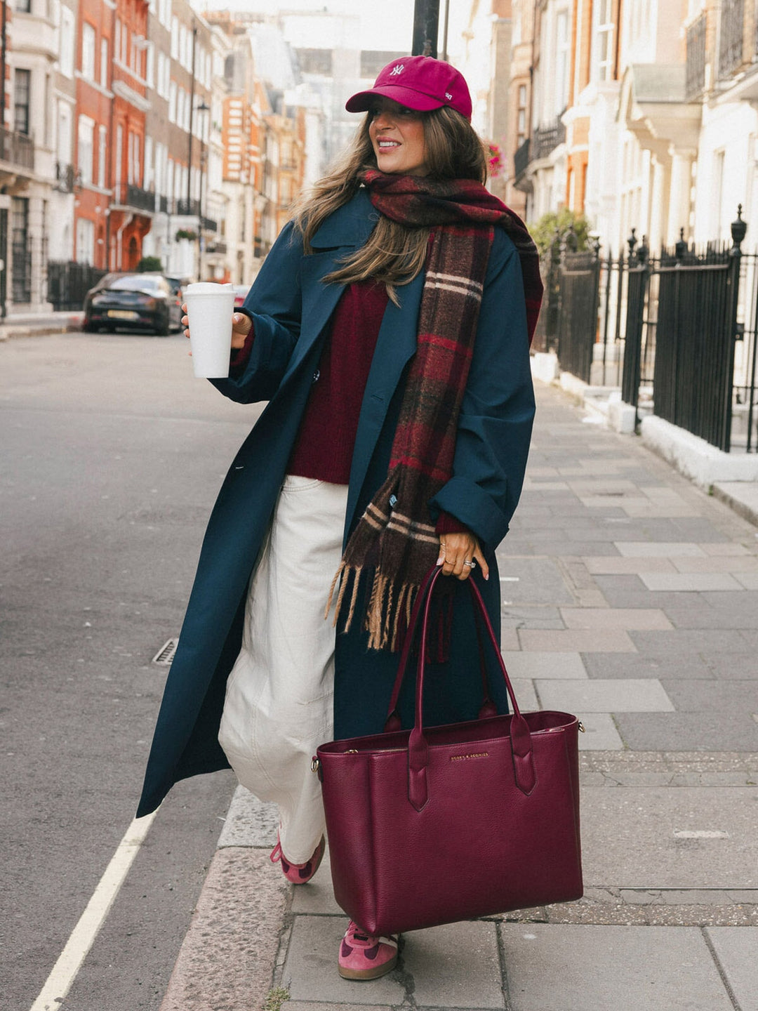 Woman carrying the Poppy & Peonies Double Duty Tote in Berry by the top handles during an everyday city commute.