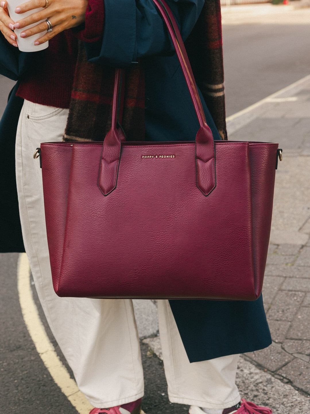 Close-up of the Poppy & Peonies Double Duty Tote in Berry carried by the top handles, showcasing the textured vegan leather finish.