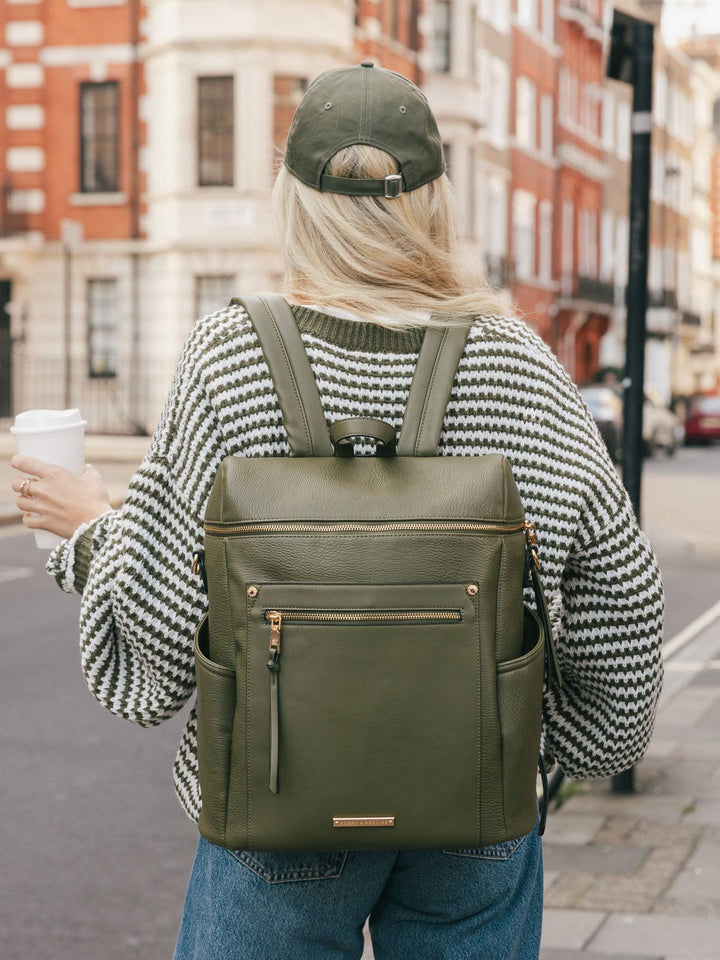 Back view of a woman wearing the Poppy & Peonies Commuter Backpack in Olive while walking outdoors.