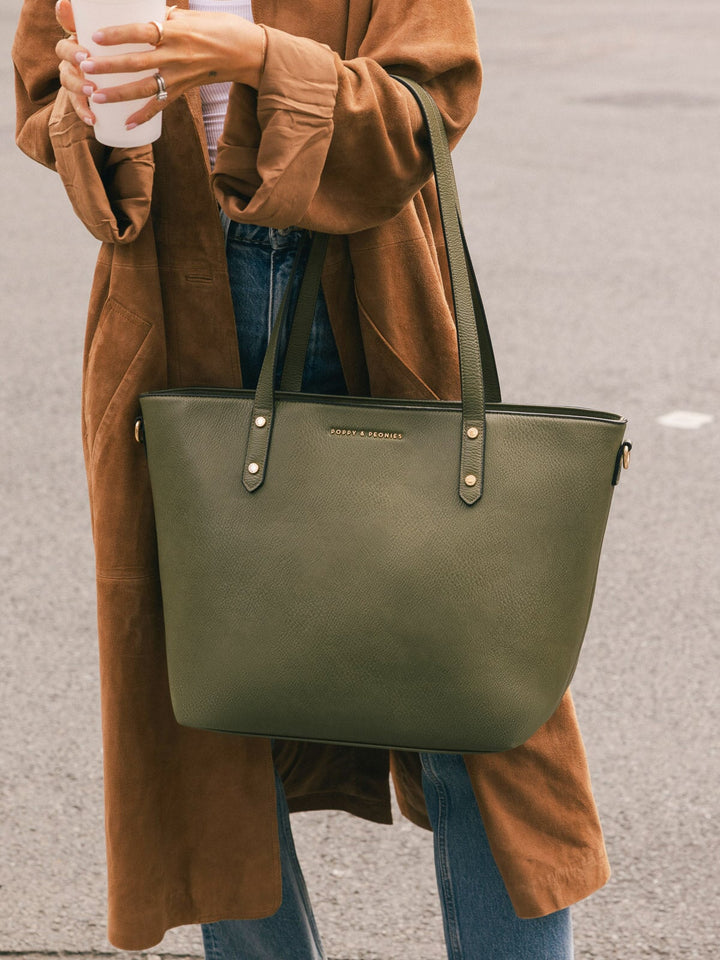 Close-up of a woman carrying the Poppy & Peonies Go-Getter Tote in Olive over her shoulder while holding a takeaway coffee.