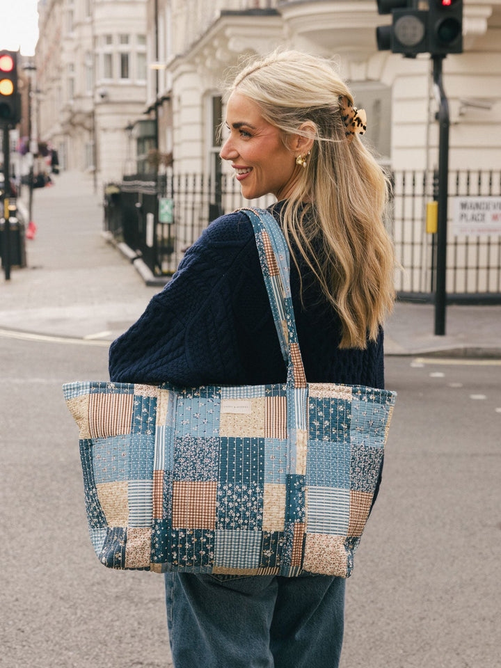 Three-quarter lifestyle shot of a woman carrying the Poppy & Peonies Daydreamer Tote in Navy Patchwork over her shoulder.