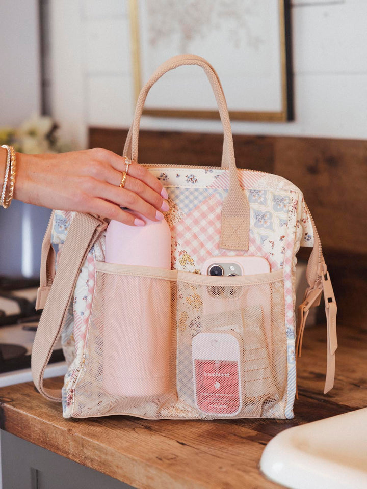 Person removing a water bottle from a patchwork lunch bag