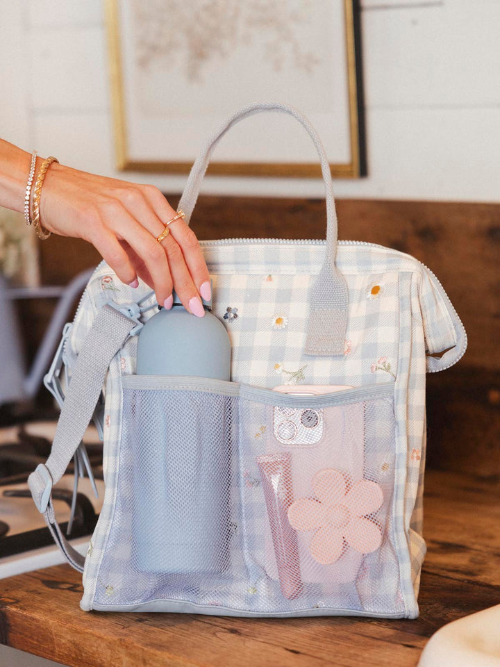 Hand removing a water bottle from a gingham lunch bag