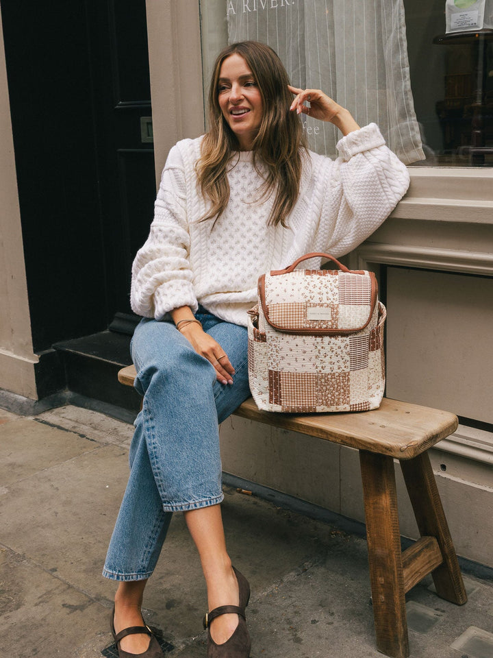 Seated lifestyle shot of a woman posing beside the Poppy & Peonies Lunch Date in Brown Patchwork.