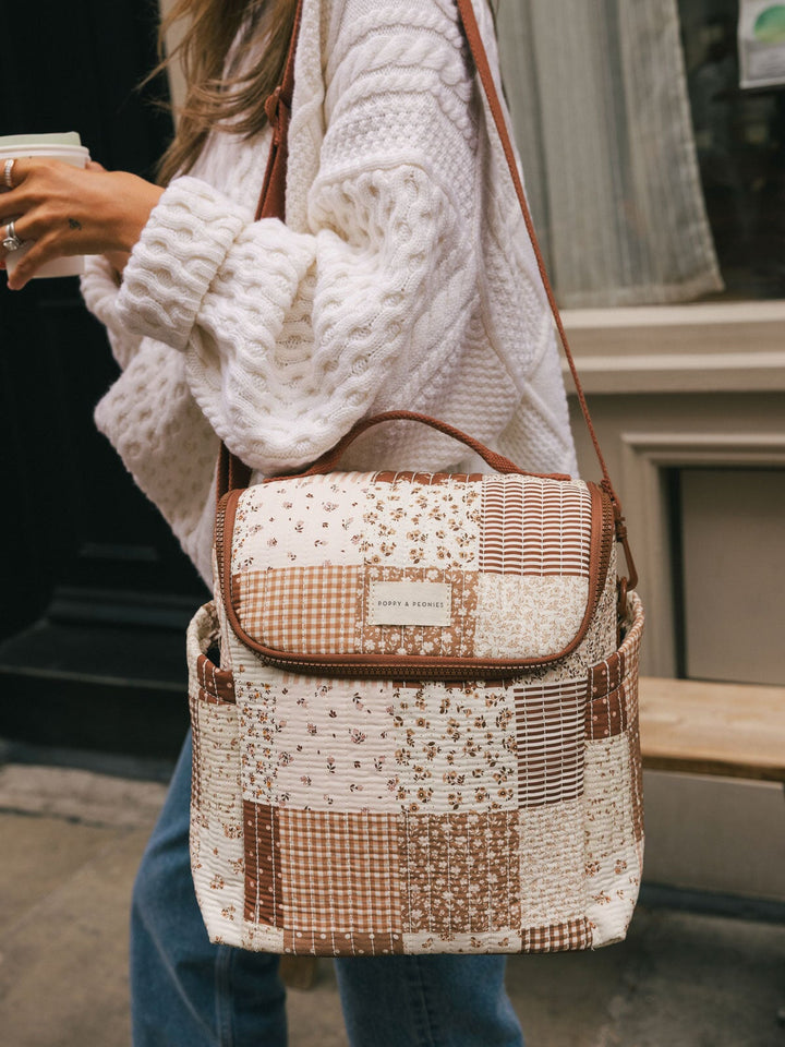 Close-up lifestyle shot of a woman carrying the Poppy & Peonies Lunch Date in Brown Patchwork over her shoulder.