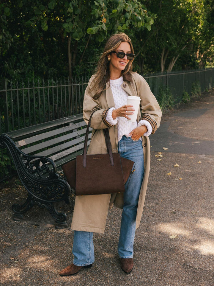 Peonies Mini Avenue Tote in Espresso Suede carried by hand while holding a coffee outdoors, highlighting its soft suede body and structured top handles.