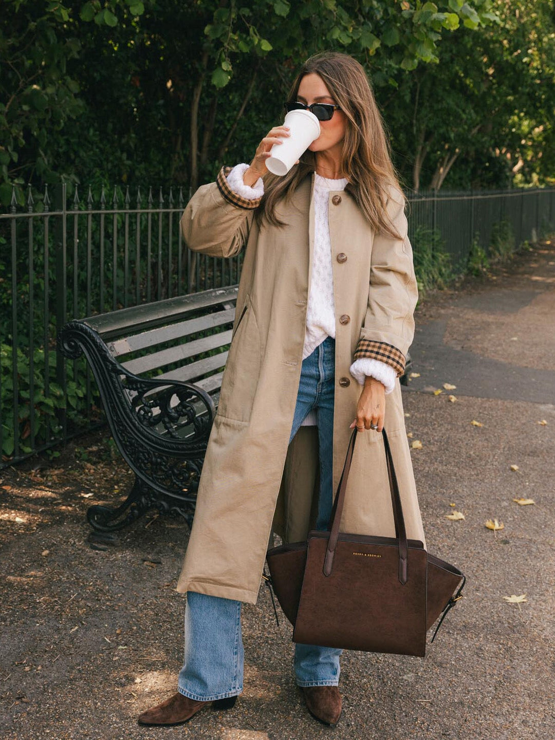 Poppy & Peonies Mini Avenue Tote in Espresso Suede carried by hand while enjoying coffee in the park, highlighting its compact silhouette and suede exterior.