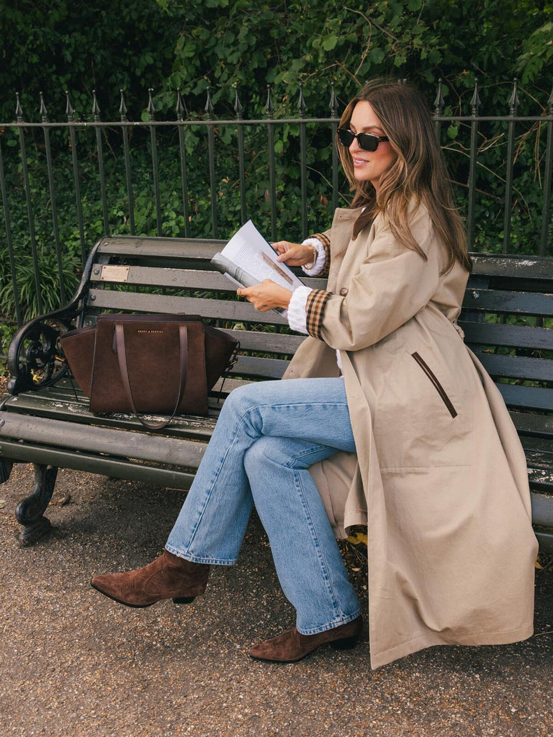 Poppy & Peonies Mini Avenue Tote in Espresso Suede displayed on a park bench beside a seated woman, showcasing its compact everyday size and structured silhouette.