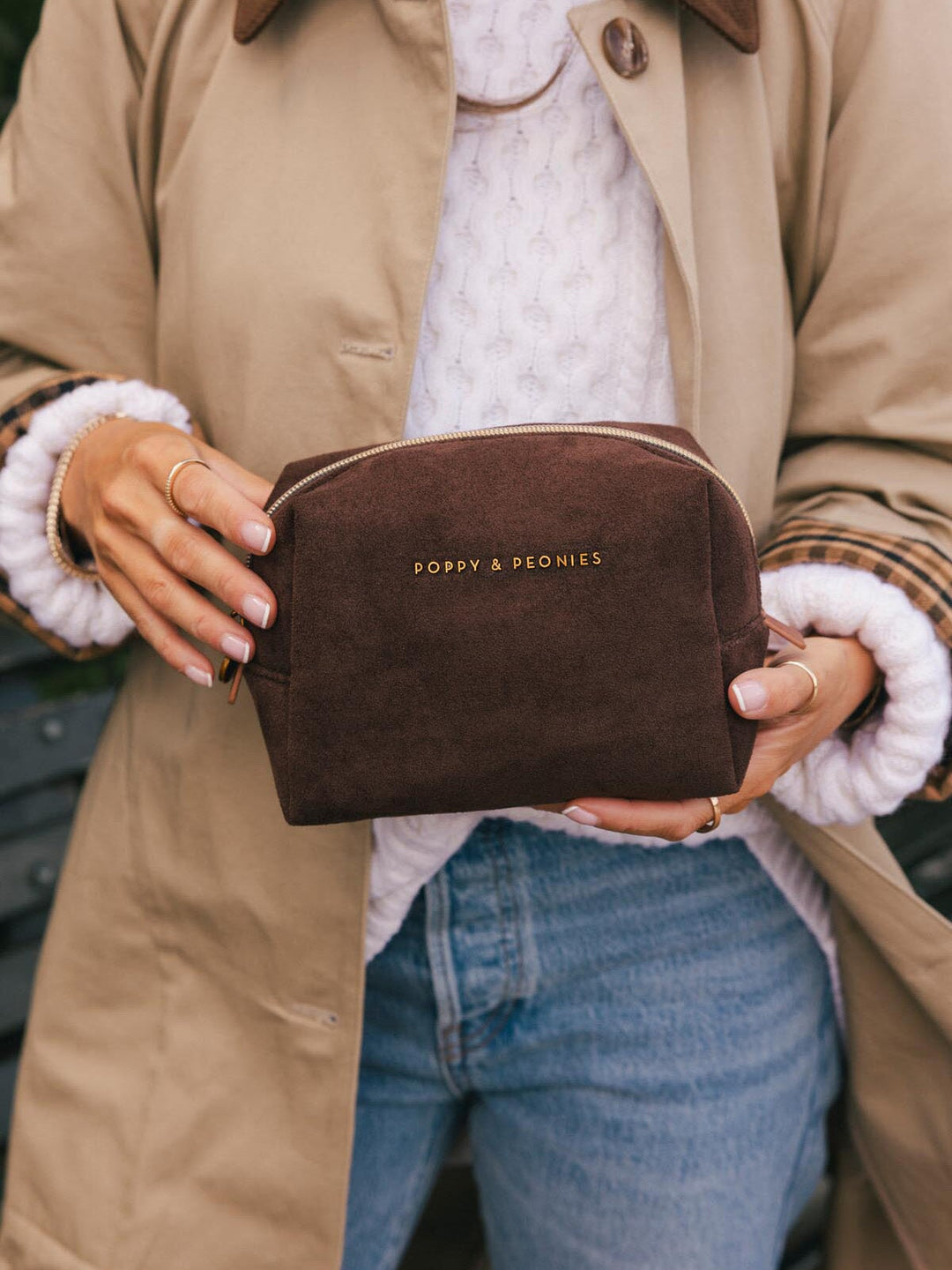 Poppy & Peonies Cosmetic Case in Espresso Suede held in hand, featuring a soft suede exterior, structured shape, zip closure and gold-tone logo.