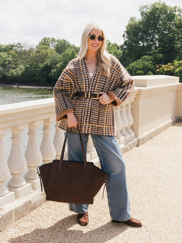 Poppy & Peonies Avenue Tote in Espresso Suede carried by hand during a sunny outdoor outing, showcasing its roomy structured shape and long top handles.