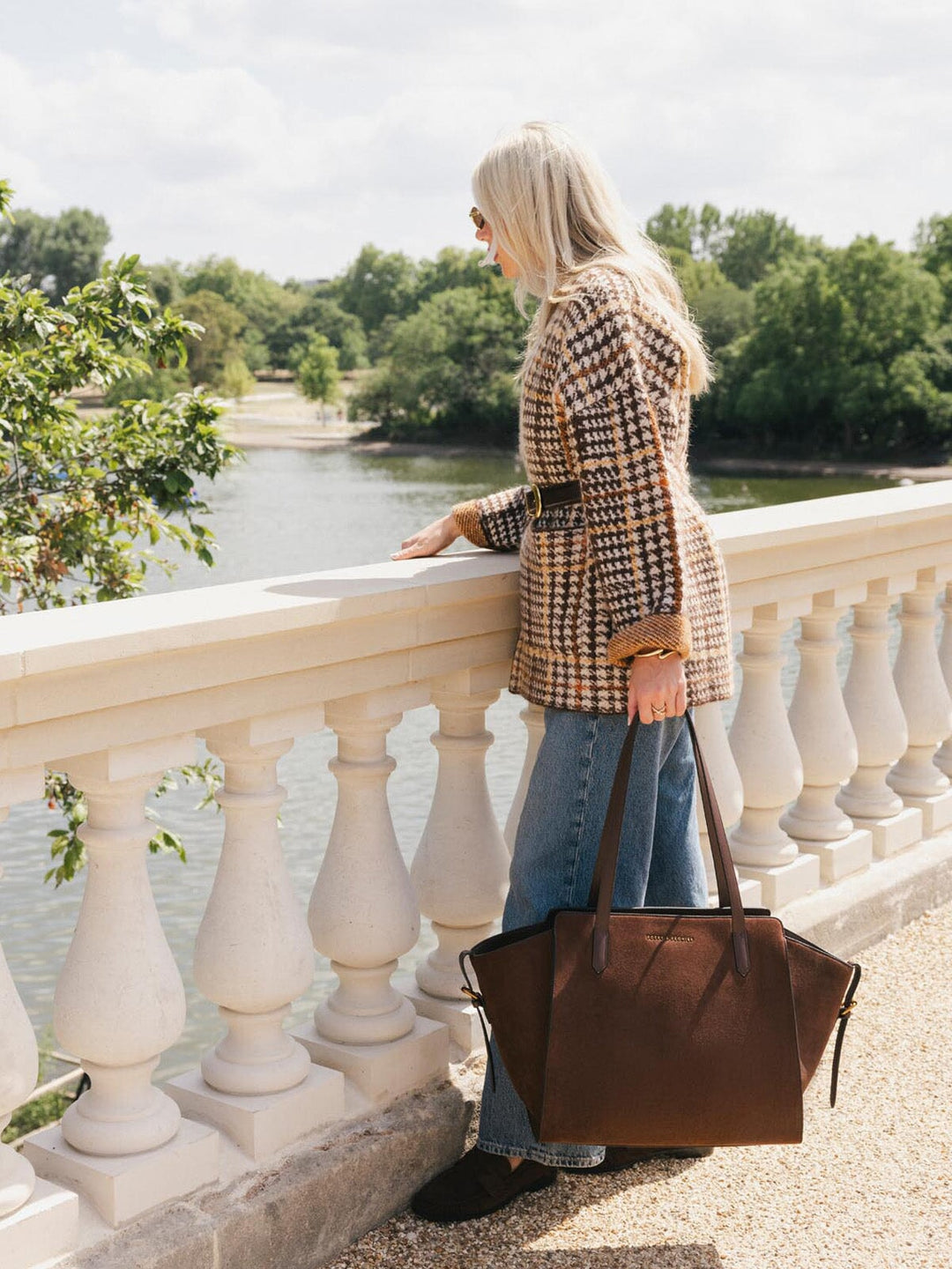 Poppy & Peonies Avenue Tote in Espresso Suede carried by hand during a waterfront walk, showcasing its spacious silhouette and long vegan leather straps.