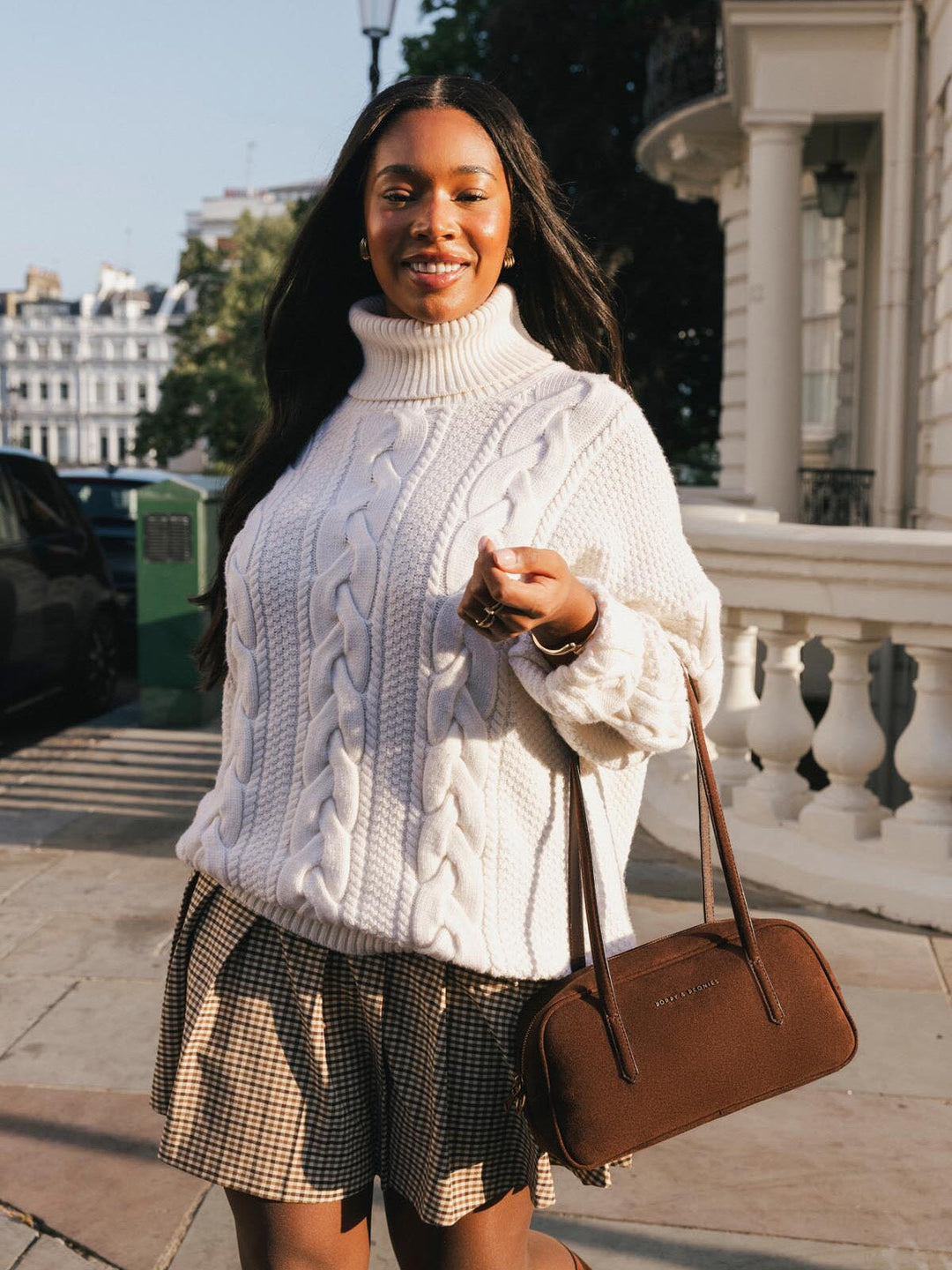 Poppy & Peonies The Friday Satchel in Espresso Suede carried by hand during a sunny outdoor outing, showcasing its compact east-west shape.