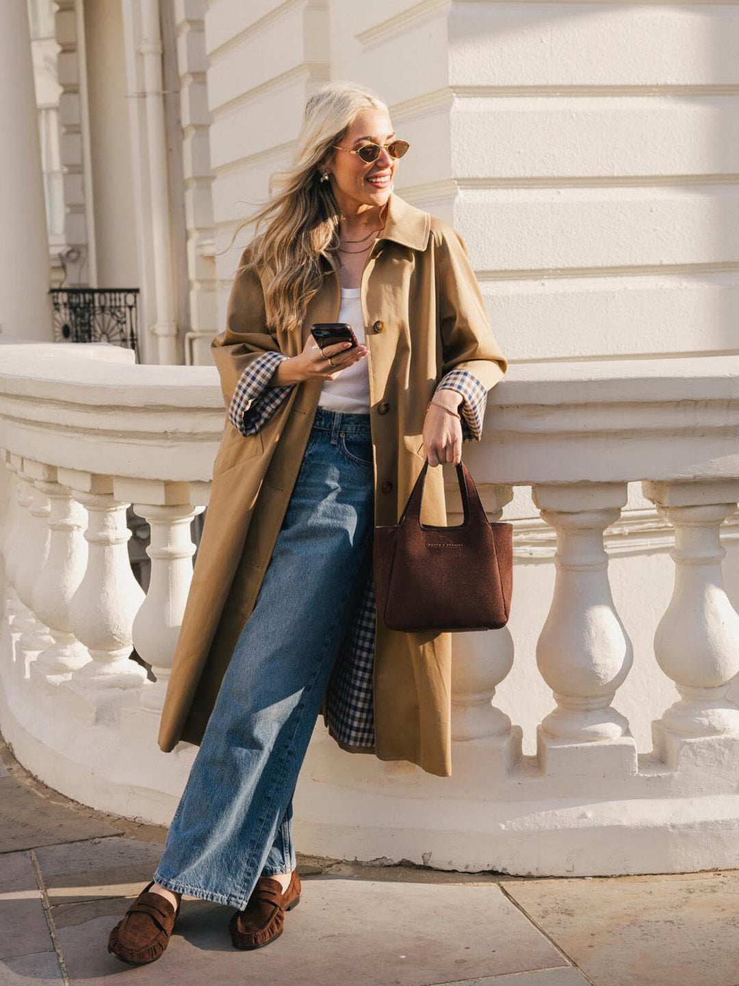 Poppy & Peonies The Pick Me Up Tote in Espresso Suede carried by hand, styled with a trench coat and jeans outdoors.