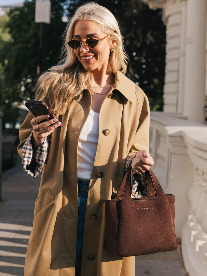 Poppy & Peonies The Pick Me Up Tote in Espresso Suede carried by hand while walking outdoors, showcasing its versatile everyday size.
