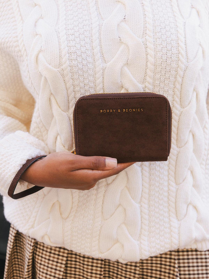 Poppy & Peonies The Grab and Go Wallet in Espresso Suede held in hand, showcasing its compact size, rich brown suede exterior and detachable wrist strap.