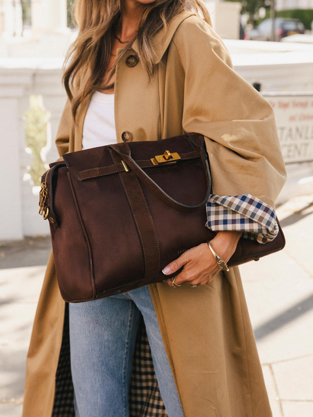 Close-up of Poppy & Peonies Effortless Tote in Espresso Suede carried outdoors, highlighting the top handles, decorative turn-lock hardware and belting detail.
