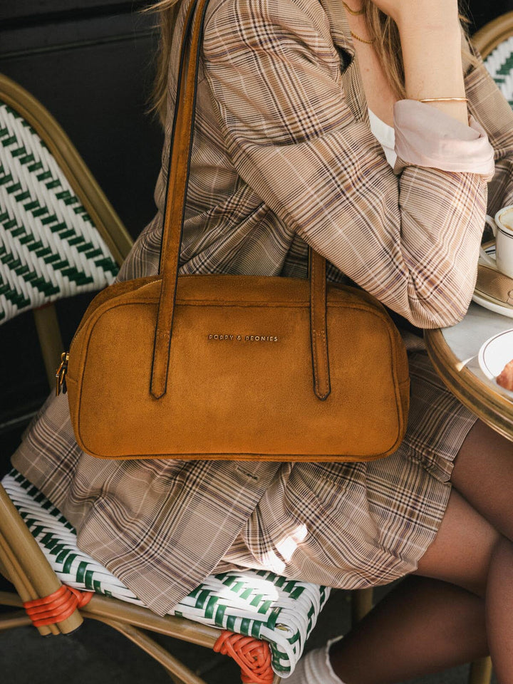 Close-up of Poppy & Peonies The Friday Satchel in Cognac Suede, showcasing its elongated east-west silhouette and structured top handles.