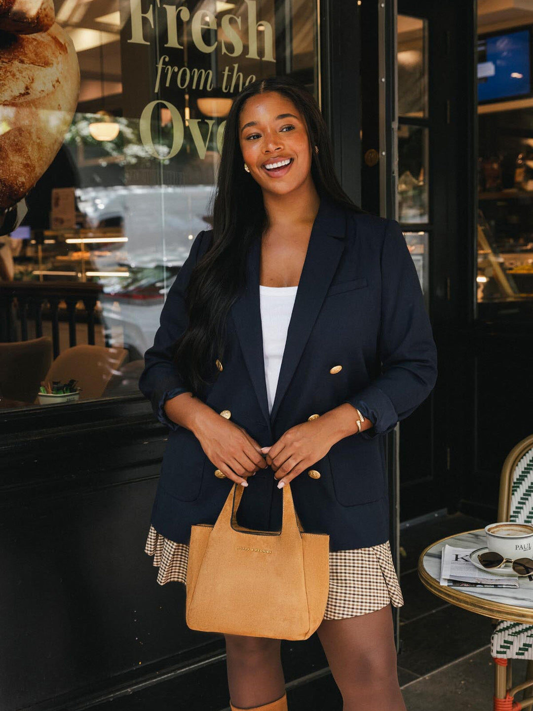 Poppy & Peonies The Pick Me Up Tote in Cognac Suede carried by the top handles, highlighting its compact shape and soft suede exterior.