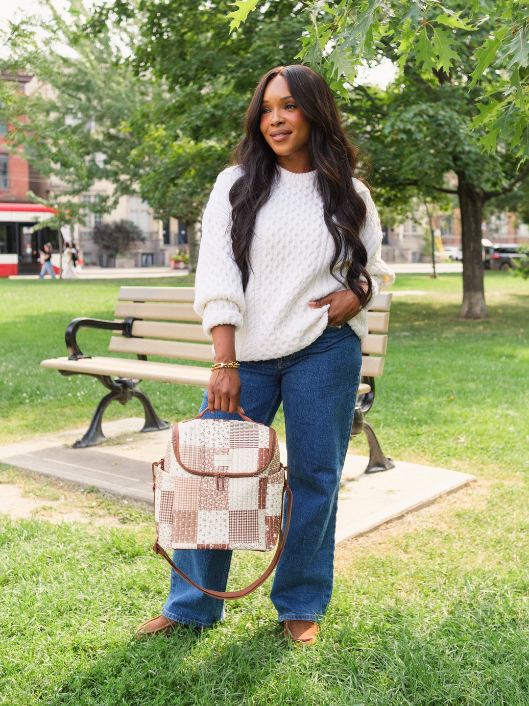 Poppy & Peonies The Lunch Date in Brown Patchwork carried by the top handle in a park.