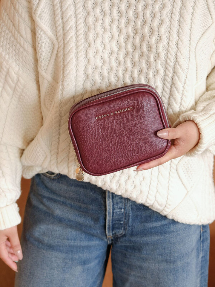 Close-up lifestyle shot of a woman holding the Poppy & Peonies Split Organizer in Berry, showcasing its structured silhouette, textured finish and zip-around closure.