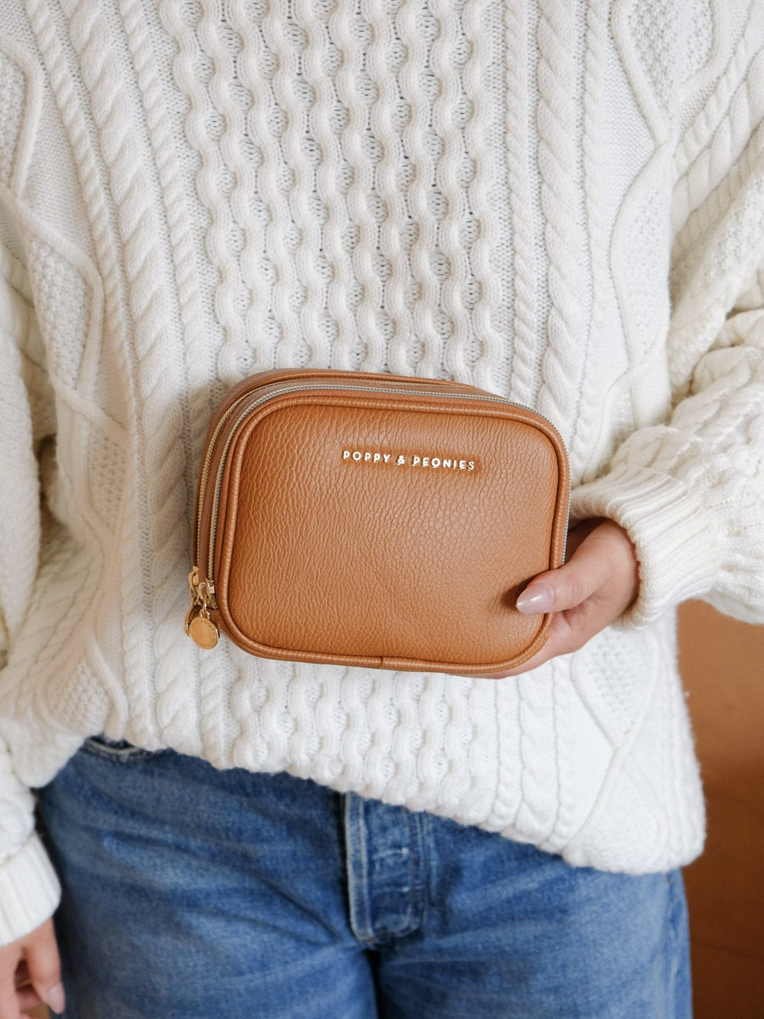 Product-focused lifestyle shot of a woman holding the Poppy & Peonies Split Organizer in Cognac, highlighting its compact rectangular design and zip closure.