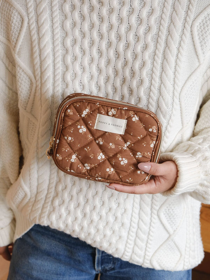Lifestyle shot of a woman holding the Poppy & Peonies Split Organizer in Brown Floral, highlighting its quilted finish and compact shape.