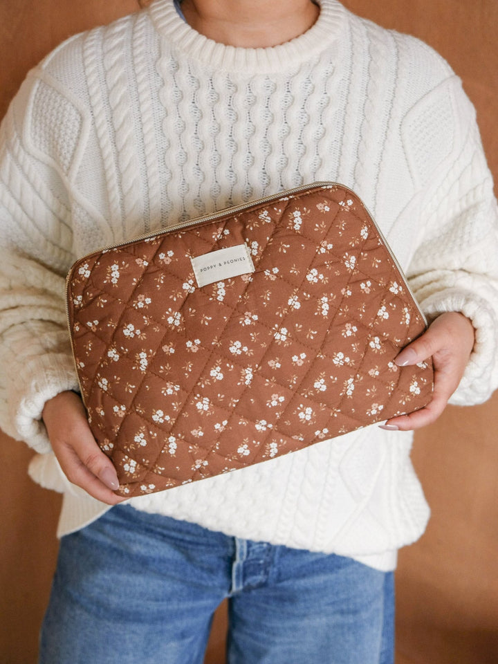 Lifestyle close-up of the Sitting Pretty Cosmetic Case in Brown Floral, highlighting its warm brown floral print, quilted finish, and spacious structured silhouette.