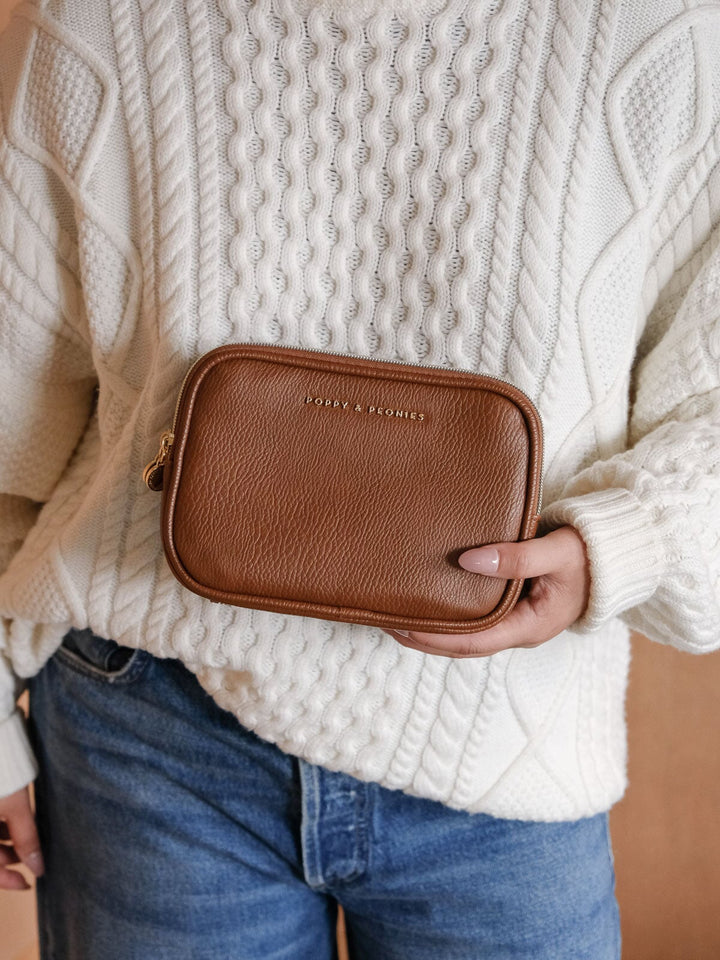 Product-focused lifestyle shot of the Poppy & Peonies Split Organizer in Chestnut, showcasing its warm brown textured finish, compact rectangular shape, and gold-tone branding.