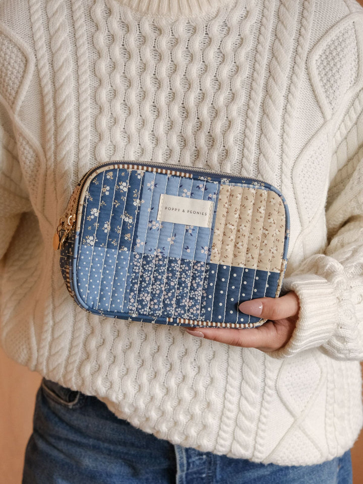 Product-focused lifestyle shot of a woman holding the Poppy & Peonies Split Organizer in Navy Patchwork, highlighting its quilted patchwork design and zip-around closure.