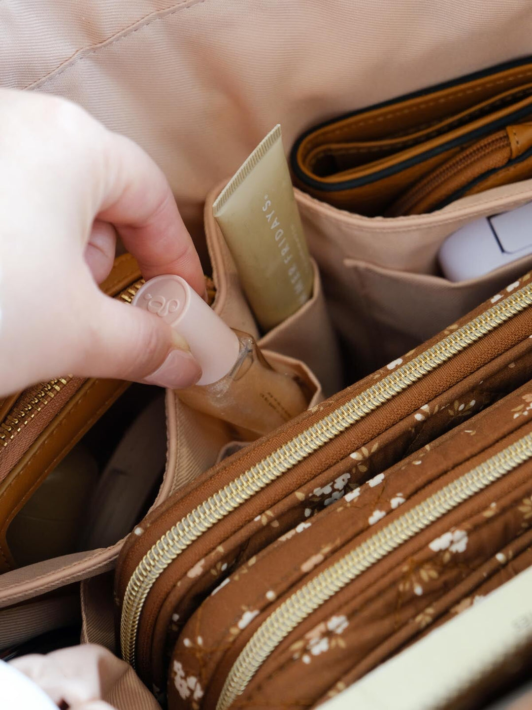 Close-up of the Daydreamer Tote in Brown Floral highlighting its interior organization with dedicated pockets holding beauty products, a wallet, and small everyday essentials.