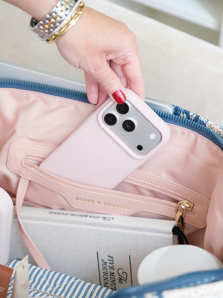 Close-up of the Daydreamer Tote in Navy Patchwork showing a phone being placed into an interior pocket alongside neatly organized everyday essentials.