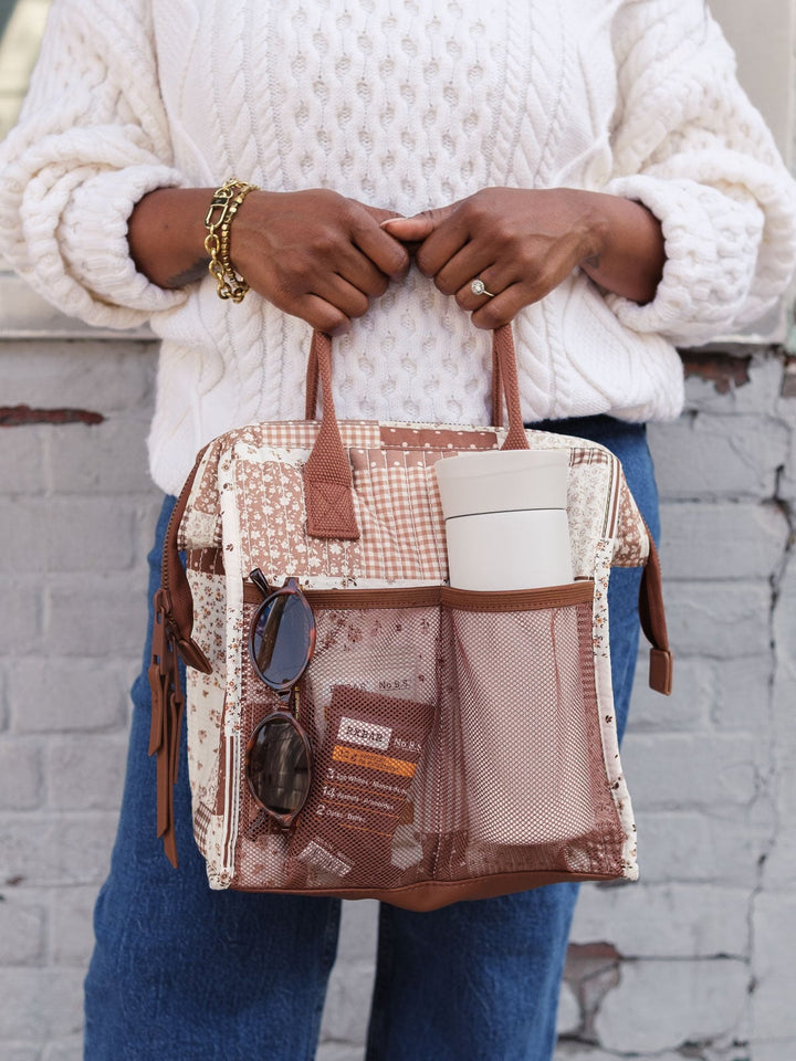 Close-up lifestyle shot of the Poppy & Peonies The Lunch Bag in Brown Patchwork with the front pocket packed with everyday essentials, highlighting its convenient exterior storage.